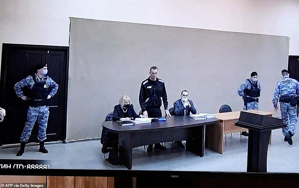 A new trial against jailed Kremlin critic Alexei Navalny began Tuesday inside the penal colony outside Moscow where he is held. A video link showed Navalny (pictured centre with his wife Yuliya Navalnaya via video link) in a prison uniform at the hearing