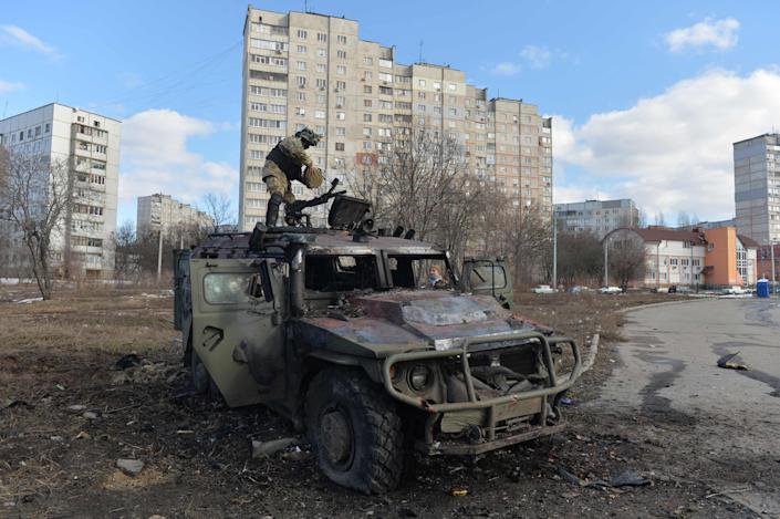 An Ukrainian Territorial Defence fighter examines a destroyed Russian Armoured personnel carrier (APC) after the fight in Kharkiv on Feb. 27, 2022. Ukrainian forces secured full control of Kharkiv on Feb. 27, 2022 following street fighting with Russian troops in the country's second biggest city, the local governor said.