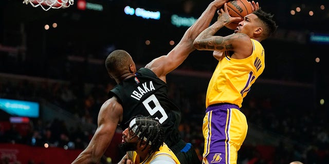Los Angeles Lakers guard Malik Monk, right, shoots as Los Angeles Clippers center Serge Ibaka, left, defends while forward Anthony Davis stands by during the first half of an NBA basketball game Thursday, Feb. 3, 2022, in Los Angeles.