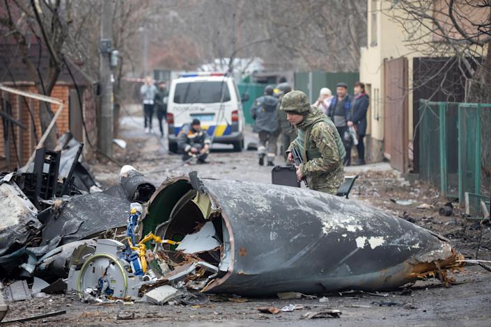 A Ukrainian Army soldier inspects fragments of a downed aircraft in Kyiv, Ukraine, Friday, Feb. 25, 2022. It was unclear what aircraft crashed and what brought it down amid the Russian invasion in Ukraine.  Russia is pressing its invasion of Ukraine to the outskirts of the capital after unleashing airstrikes on cities and military bases and sending in troops and tanks from three sides.