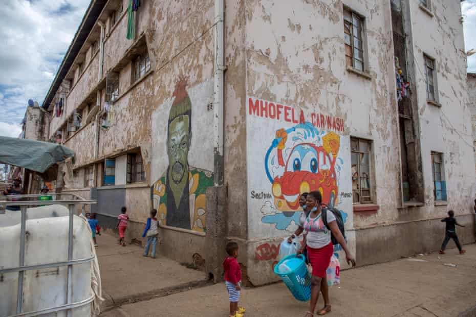 People walk past murals painted by Basil Matsika in Mbare.