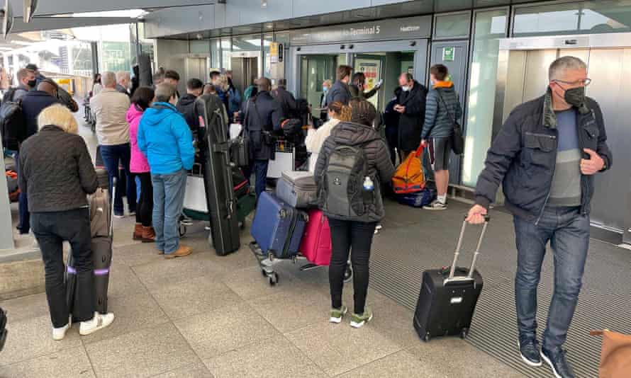 People queuing with luggage at Heathrow airport.