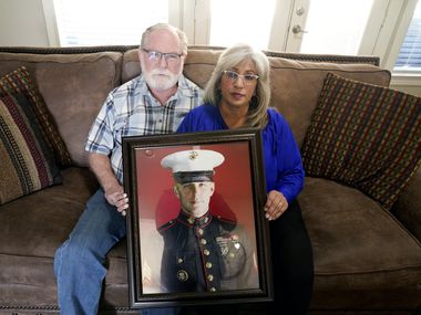 Joey and Paula Reed pose for a photo with a portrait of their son Marine veteran and Russian...