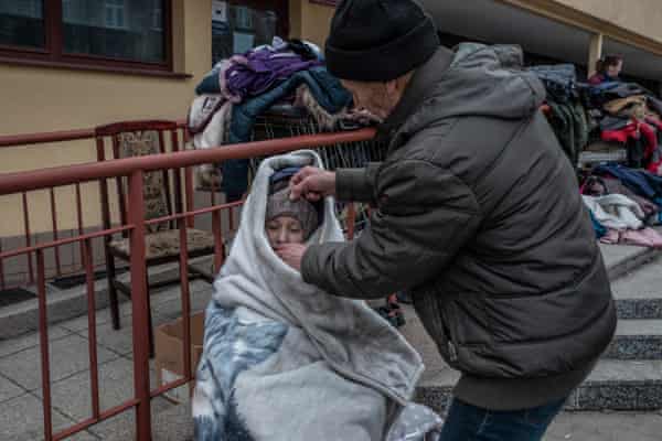 A father covers his child with a blanket offered by volunteers at the train station of Przemyśl in Poland.
