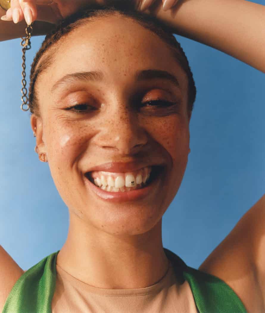 A portrait of Adwoa Aboah smiling, with her arms folded over her head