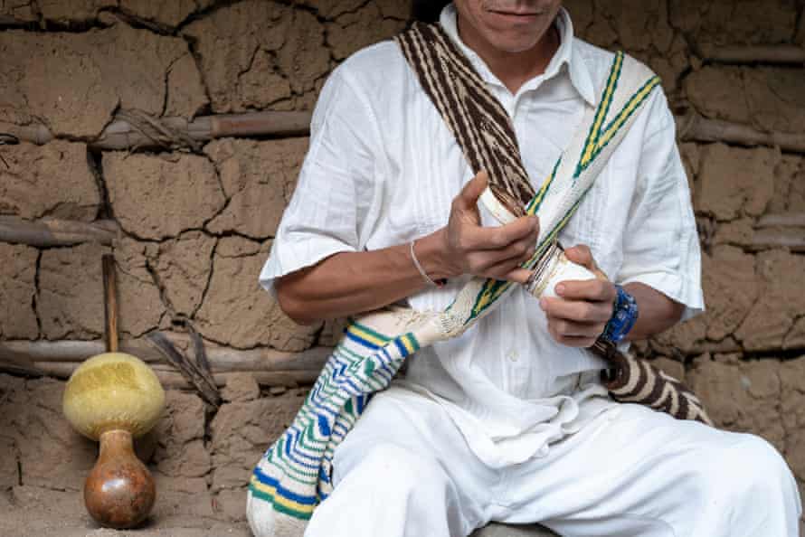 A Kankuamo elder takes some ambil, a black paste made from cooked tobacco leaves, from a pot