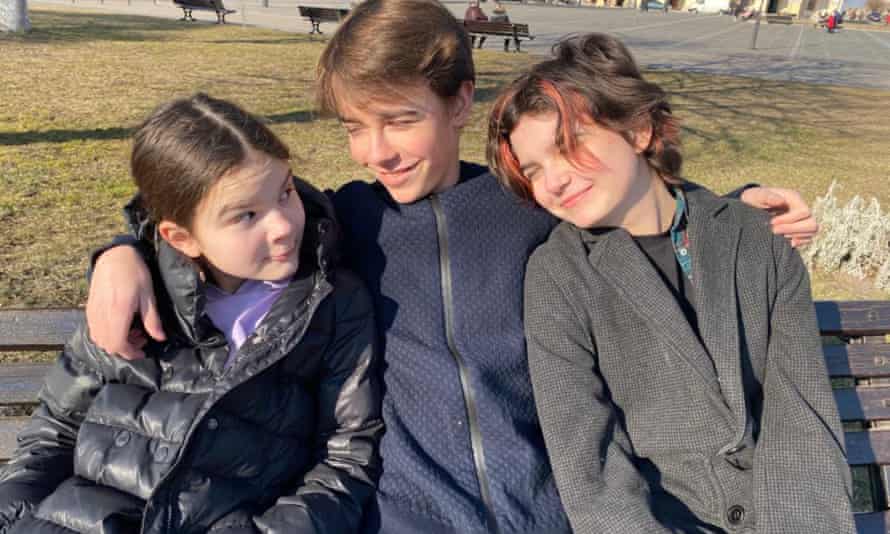 Padalko's children Katia, 11, Mykhailo, 15, and Maria, 13, sitting on a bench hugging.