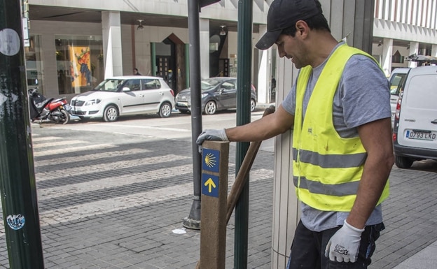 A worker placing one of the Camino de Santiago signs at the intersection between Juan Carlos I and Menacho. 