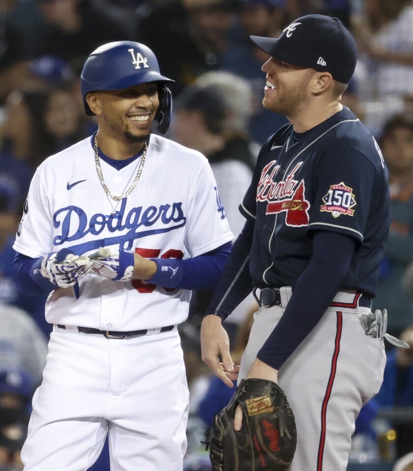 Dodgers' Mookie Betts has a laugh with Atlanta Braves first baseman Freddie Freeman.