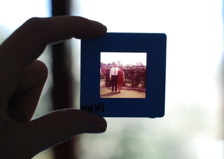 Hand holding a slide against the light where the photo of a marriage from several decades ago is left.