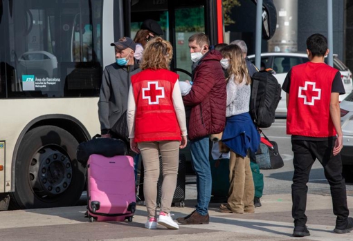 Voluntarios de la Cruz Roja acompañan a un joven ucraniano y a su bebé hasta el autobús, tras llegar a la estación de Sants