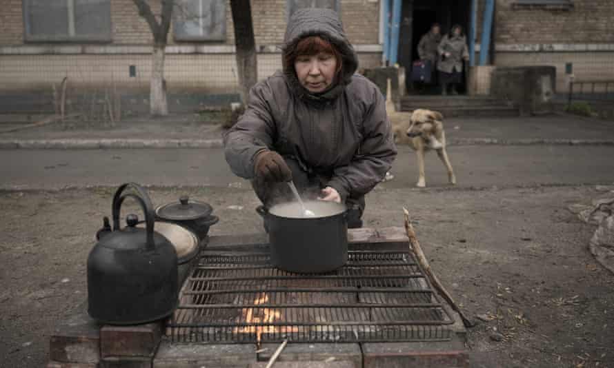 A woman cooks on an open fire outside an apartment building which according to residents has no gas, water, electricity and heating for more than a month in the formerly Russian-occupied Kyiv suburb of Bucha, Ukraine.