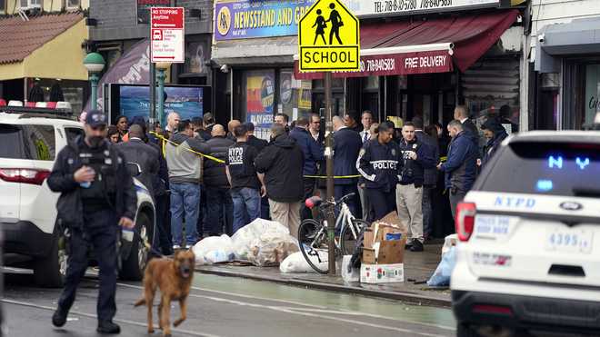 New York City Police Department personnel gather at the entrance to a subway stop in the Brooklyn borough of New York, Tuesday, April 12, 2022.
