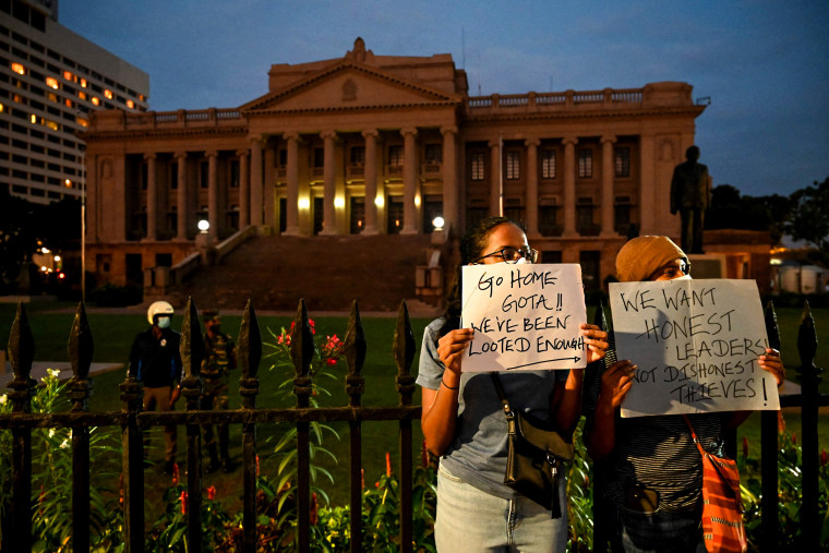Demonstrators hold placards as they take part in a protest against the economic crisis at the entrance of the president's office in Colombo, Sri Lanka, on April 10, 2022.