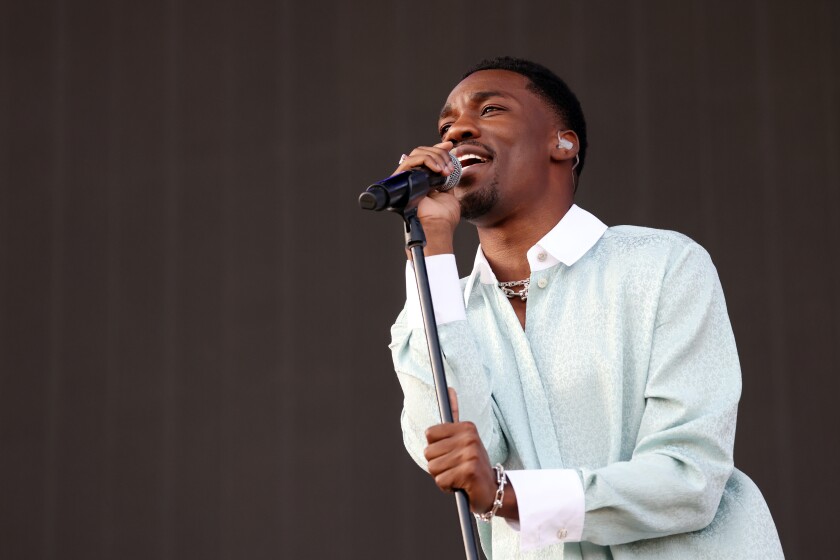 A male singer in a button-down shirt performs onstage