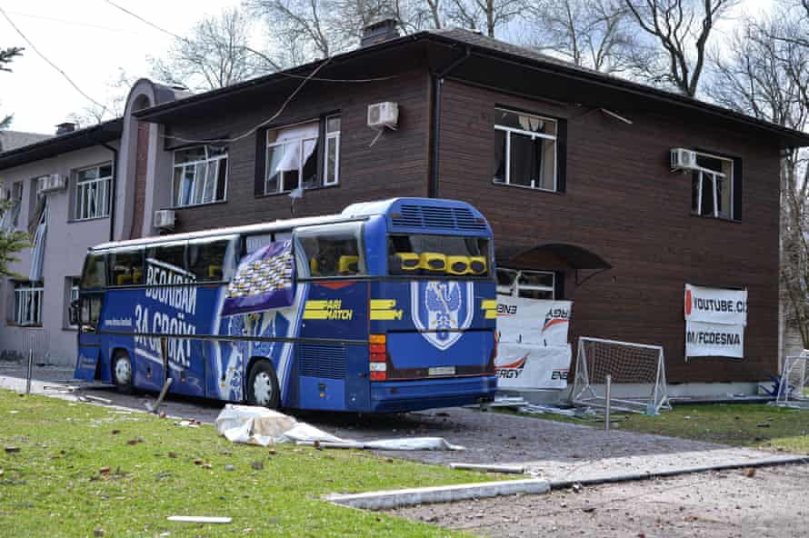 A team bus next to a damaged building at the training center.
