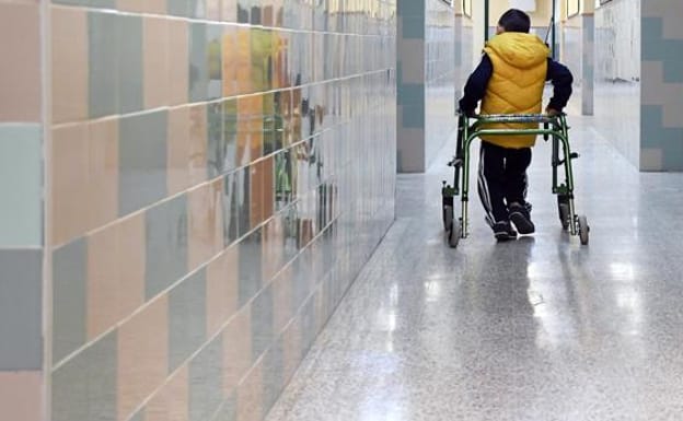 A child with a disability walks down the hall of a school. 