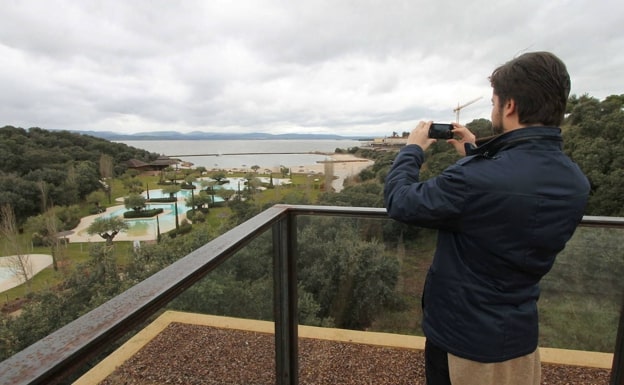 A visitor to the complex, in the social club building, photographing the artificial beach area with the reservoir in the background.