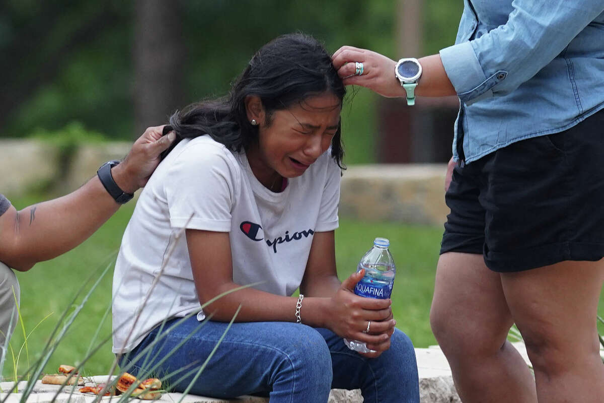 A girl cries, comforted by two adults, outside the Willie de Leon Civic Center where grief counseling will be offered in Uvalde, Texas, on May 24, 2022. - A teenage gunman killed 18 young children in a shooting at an elementary school in Texas on Tuesday, in the deadliest US school shooting in years. The attack in Uvalde, Texas -- a small community about an hour from the Mexican border -- is the latest in a spree of deadly shootings in America, where horror at the cycle of gun violence has failed to spur action to end it. (Photo by allison dinner / AFP) (Photo by ALLISON DINNER/AFP via Getty Images)