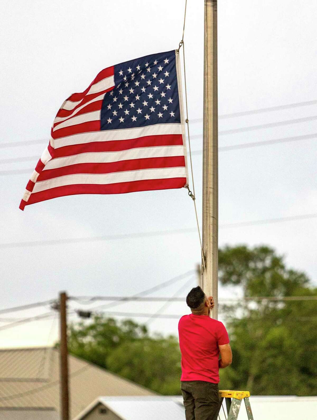 Janish Patel lowers the flag to half staff Tuesday, May 24, 2022 at his Uvalde hotel hours after a gunman entered Robb Elementary School in Uvalde and killed at least 18 children and three adults.