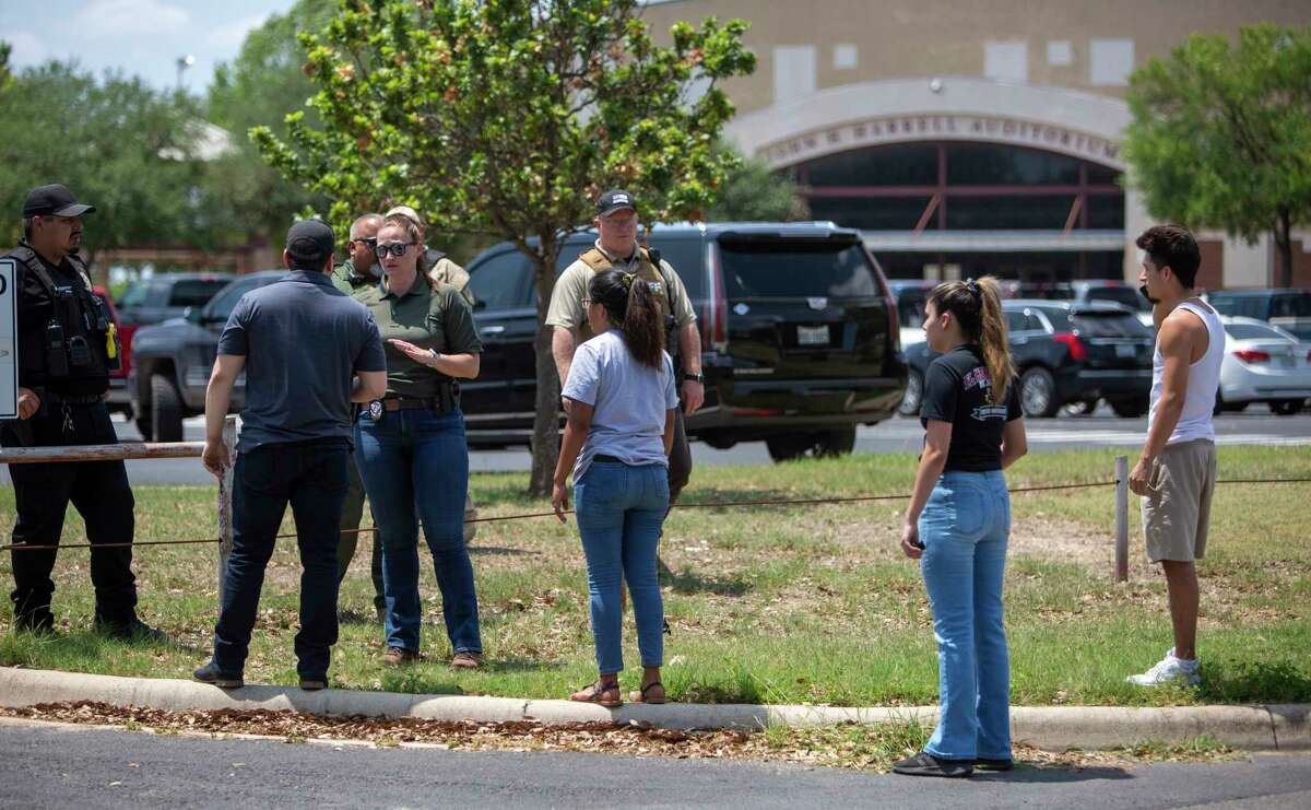 A law enforcement officer tells people that Uvalde High School is secure after a school shooting at the nearby Robb Elementary School.