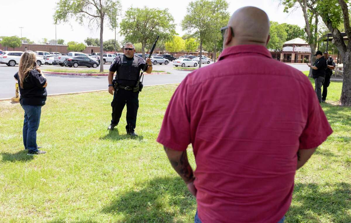A law enforcement officer tells people that Uvalde High School is secure after a school shooting at the nearby Robb Elementary School.