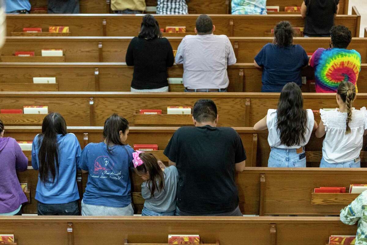 People pray Tuesday evening, May 24, 2022 at Sacred Heart Church in Uvalde after a gunman earlier in the day entered Robb Elementary School and killed at least 18 children and three adults.