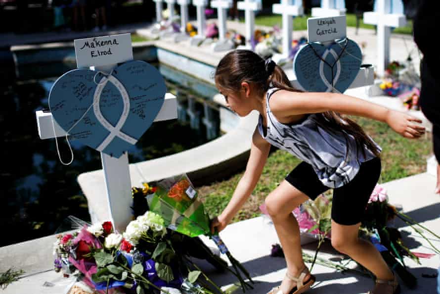 A girl leaves flowers at the memorial in Town Square, Uvalde.