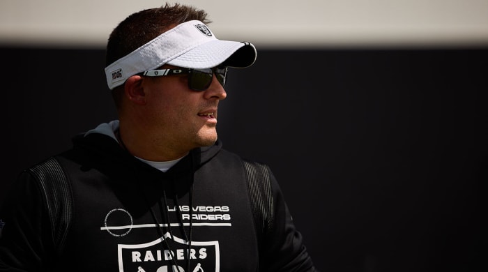 Josh McDaniels looks into the distance at practice wearing a Raiders visor.